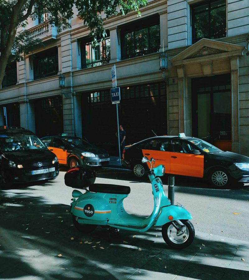 Vespa con taxis de fondo en una parada